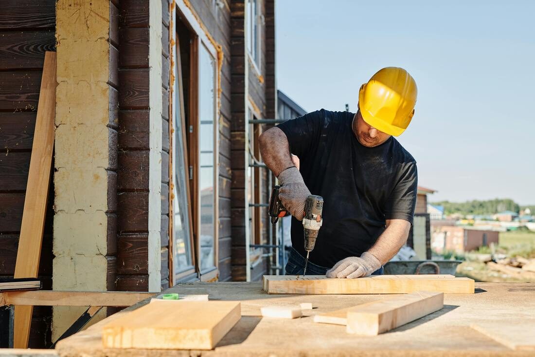 NZ carpenter in a hard hat drilling timber on a residential building site - builder CV writing