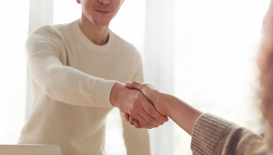 Job candidate confidently shaking hands with an interviewer after a successful job interview - interview coaching New Zealand