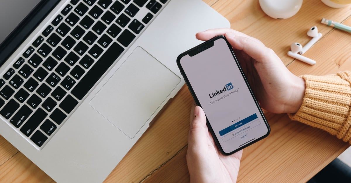 New Zealand professional opening LinkedIn on her phone to review her professionally written LinkedIn profile